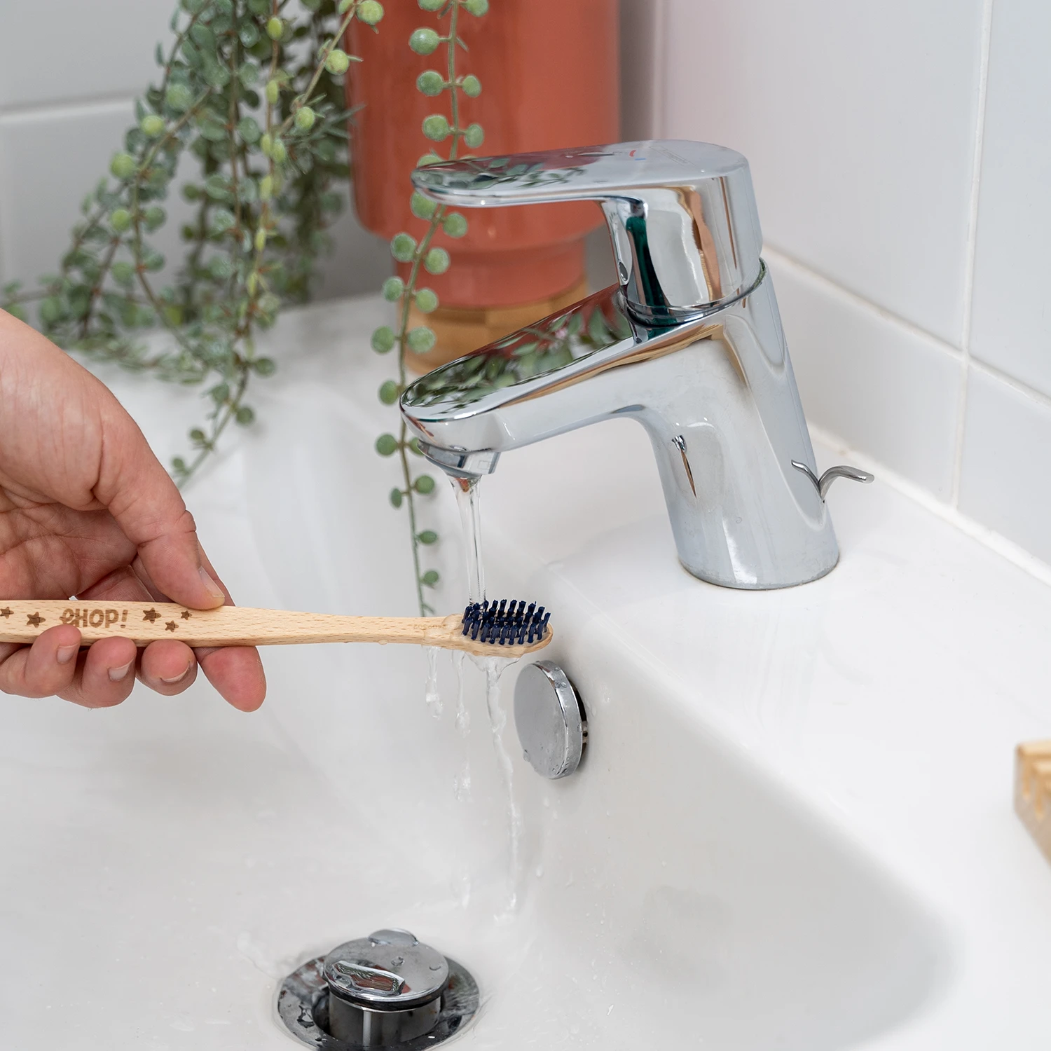 Brosse à dents en bois ehop rincée sous le robinet d'un lavabo